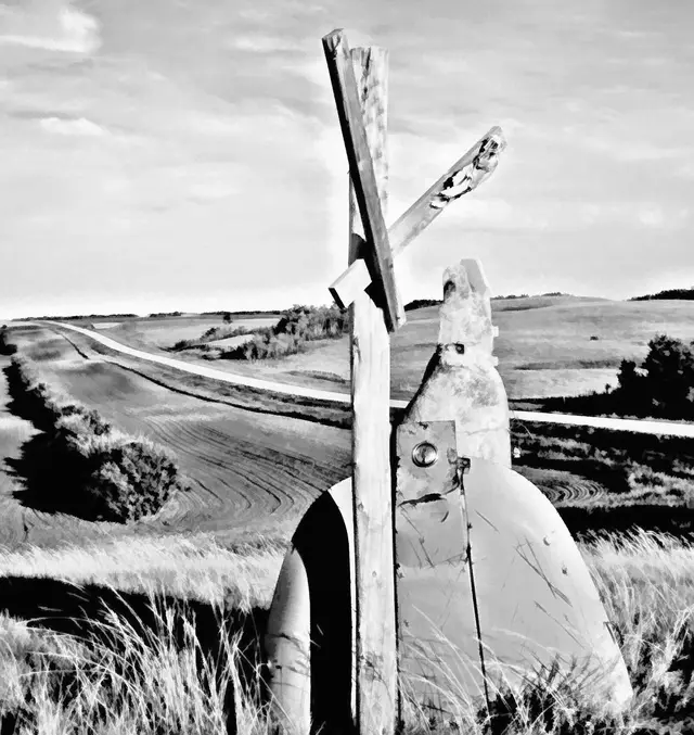 Old mailbox and wooden post overlooking rolling farmland